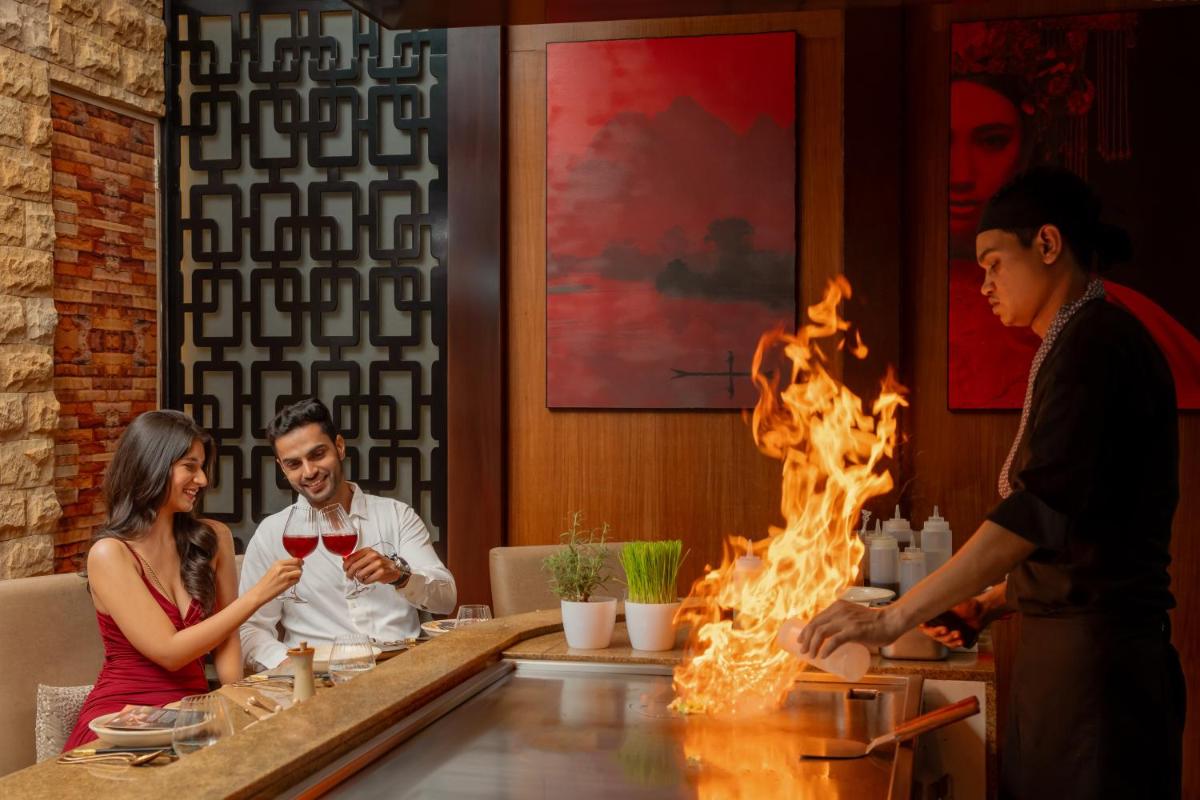a group of people sitting around a bar in a restaurant at Hyatt Pune in Pune