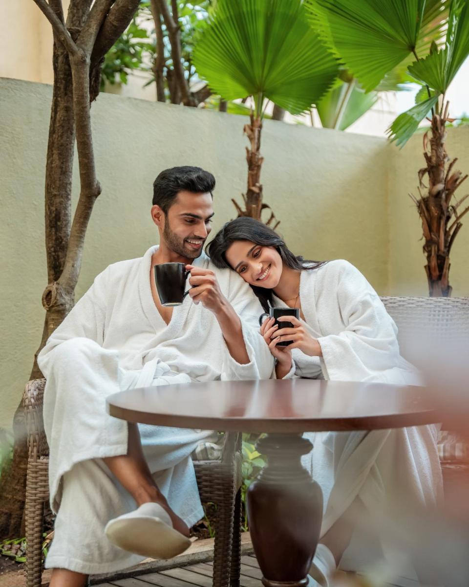 a man and woman sitting at a table looking at their cell phones at Hyatt Pune in Pune