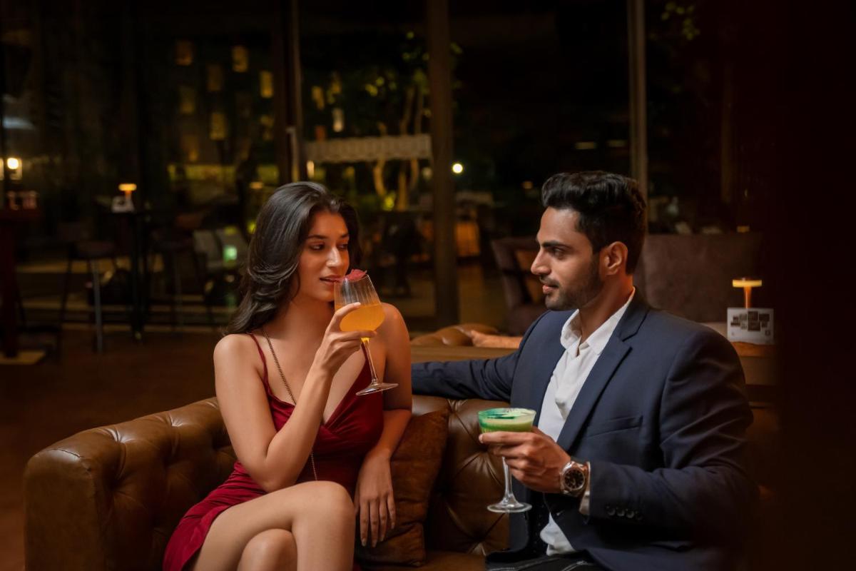 a man and woman sitting on a couch drinking wine at Hyatt Pune in Pune