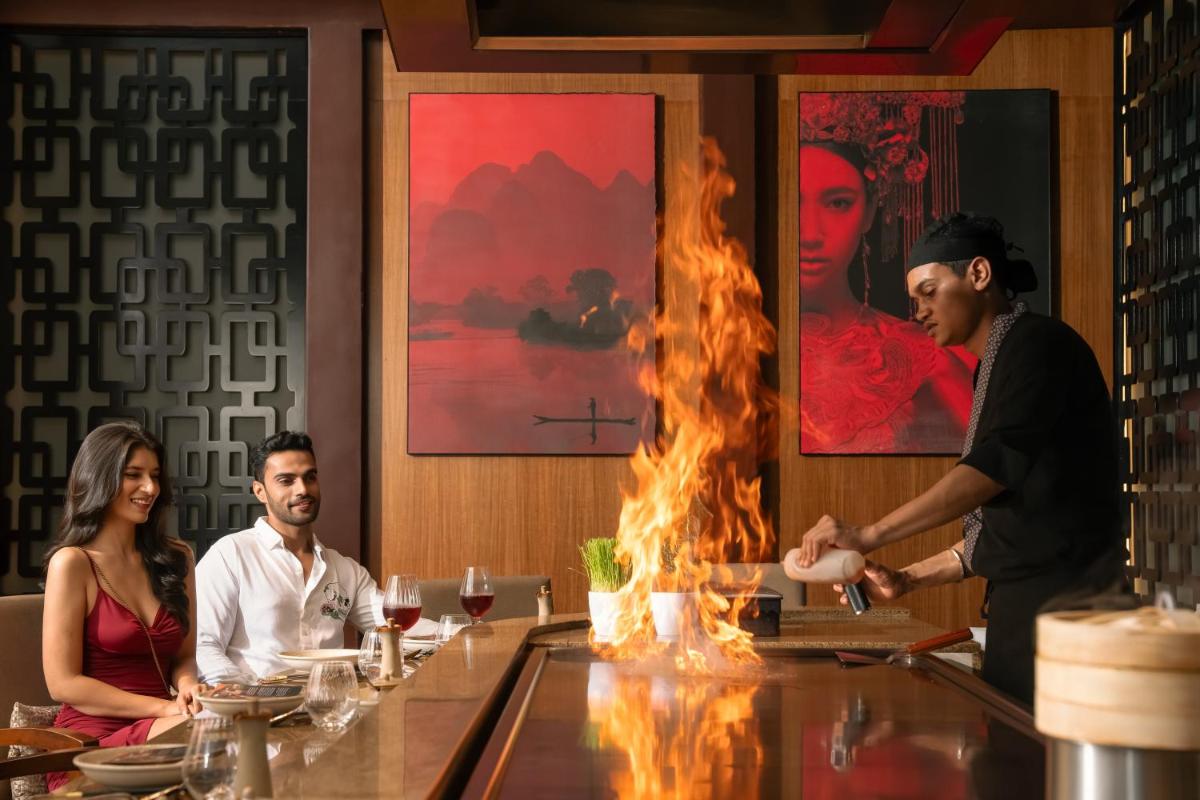 a man standing at a bar in a restaurant with flames at Hyatt Pune in Pune