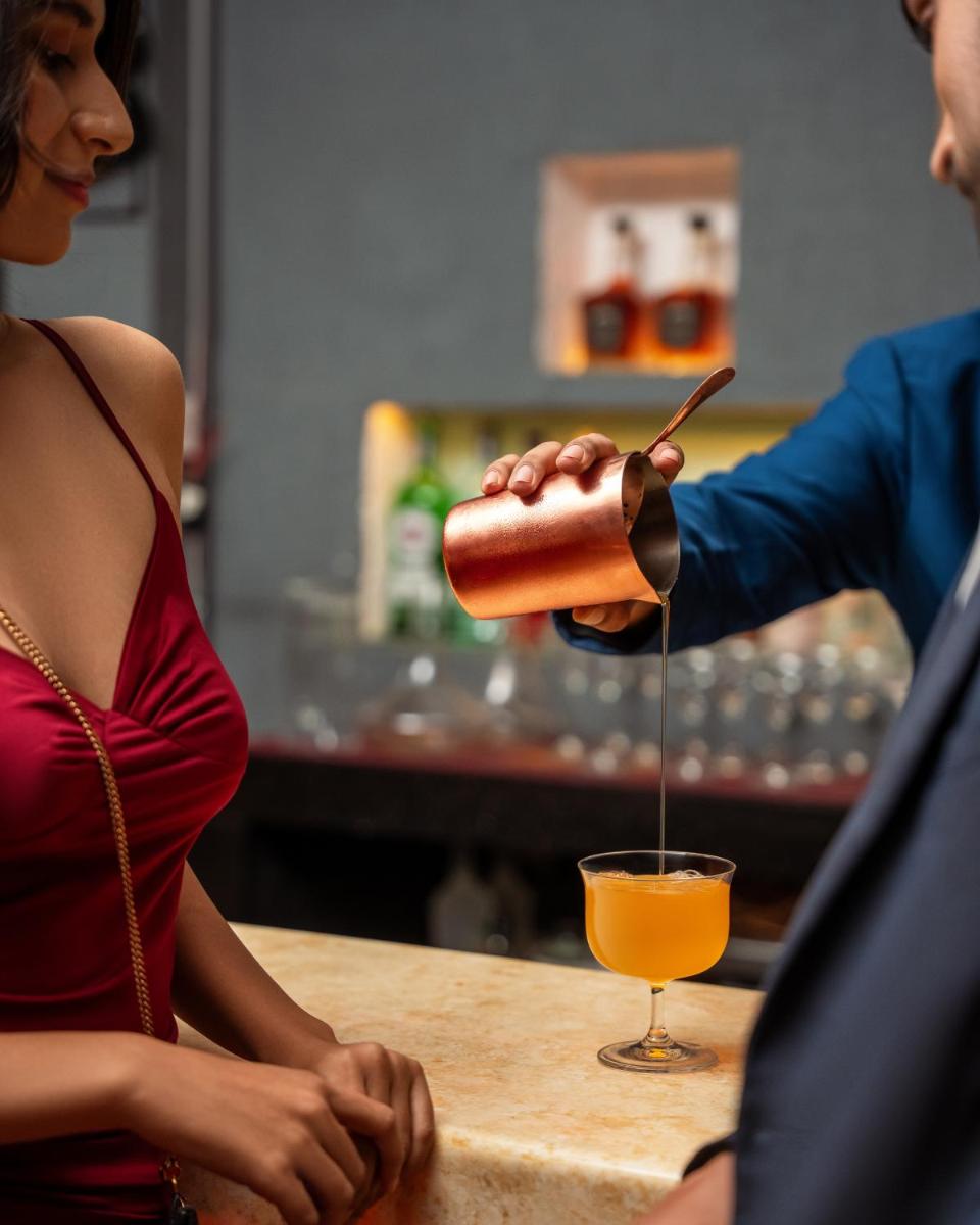 a woman standing at a bar pouring a drink at Hyatt Pune in Pune