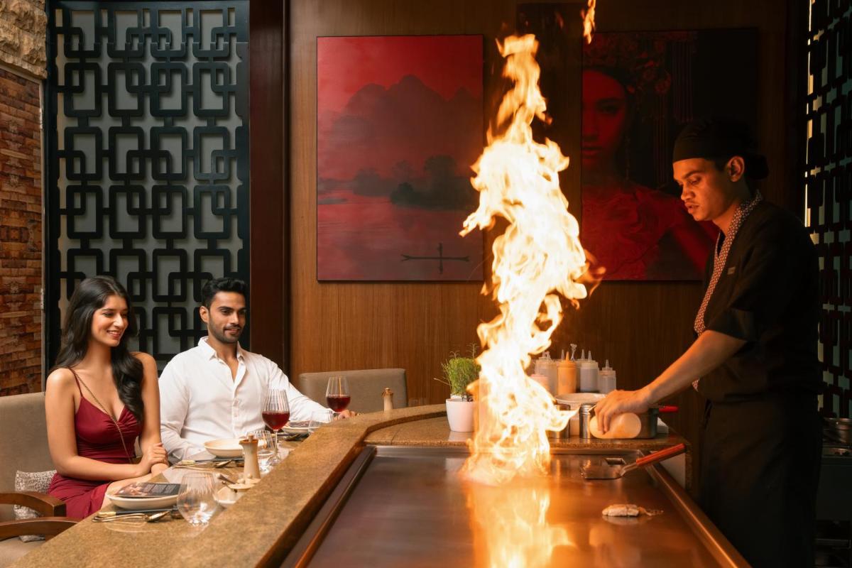 a man cooking food in a restaurant with fire on the counter at Hyatt Pune in Pune