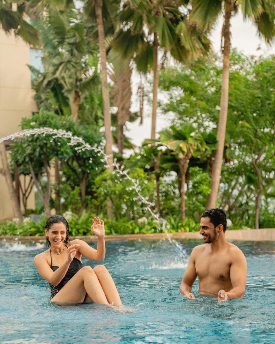 a man and a woman sitting in a swimming pool at Hyatt Pune in Pune