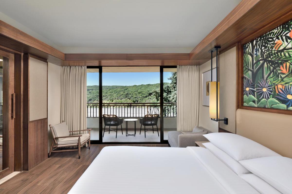 a bedroom with a bed and a view of a balcony at Courtyard by Marriott Mahabaleshwar in Mahabaleshwar