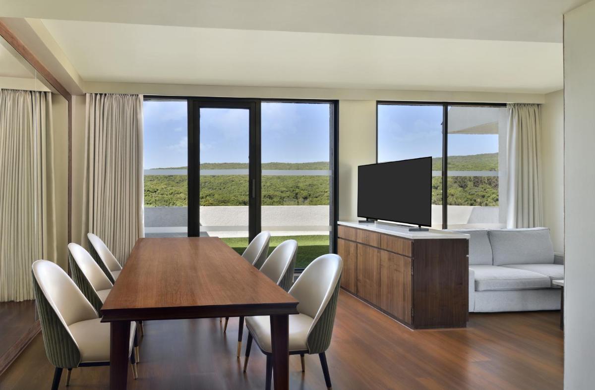 a living room with a table and a tv and chairs at Courtyard by Marriott Mahabaleshwar in Mahabaleshwar