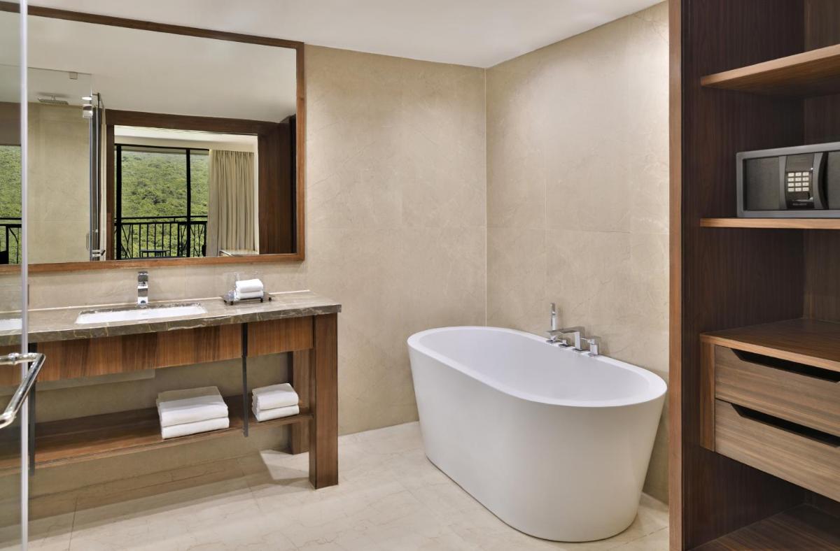 a bathroom with a tub and a sink and a mirror at Courtyard by Marriott Mahabaleshwar in Mahabaleshwar