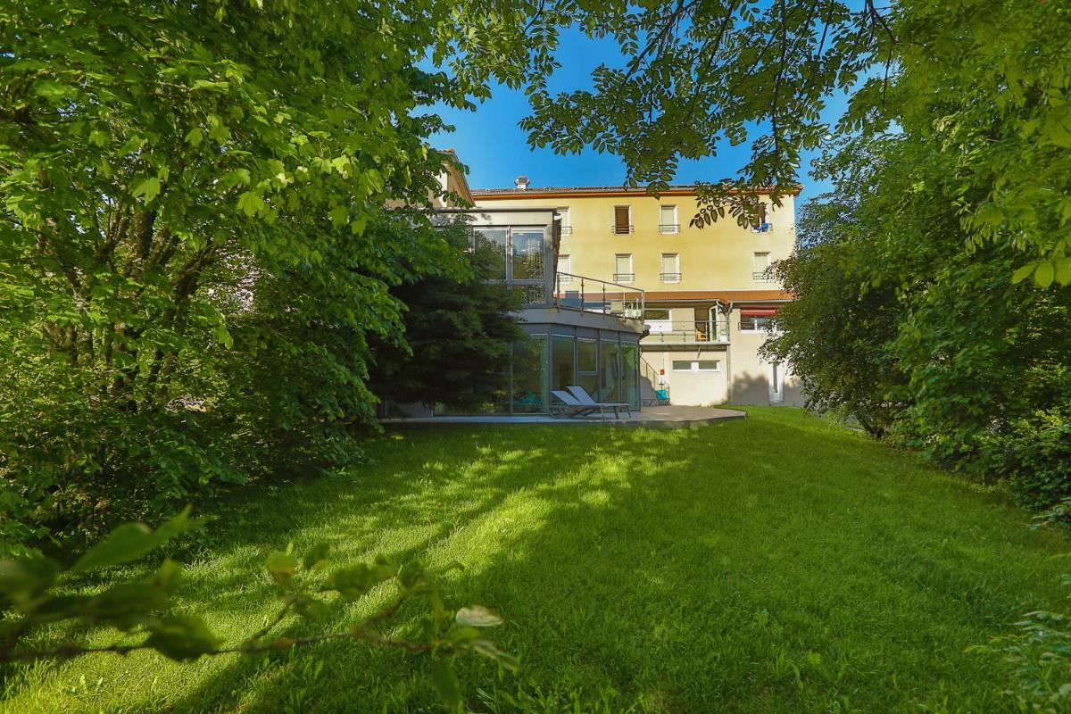 un grand jardin avec un bâtiment en arrière-plan dans l'établissement Logis Hotel Spa Restaurant Le Provence, à Lanarce