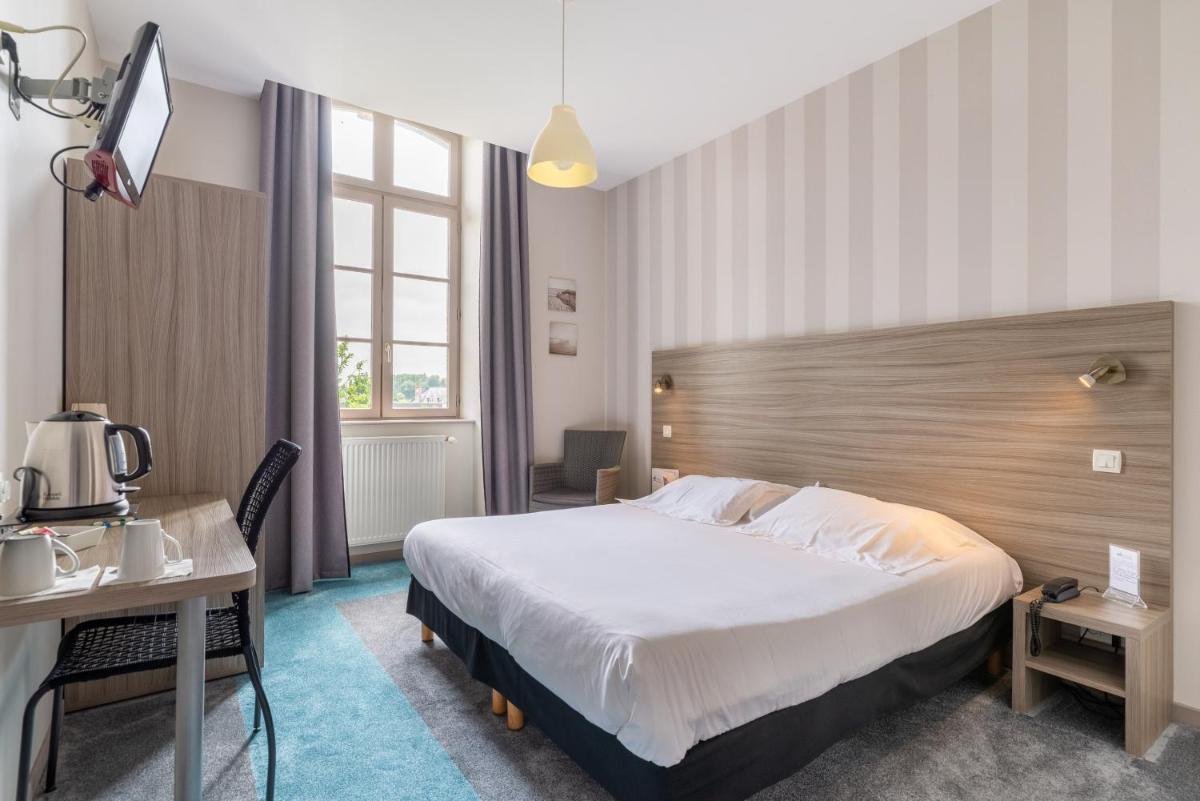 une chambre d'hôtel avec un grand lit et un bureau dans l'établissement Brit Hotel Spa Le Connetable, à Dinan