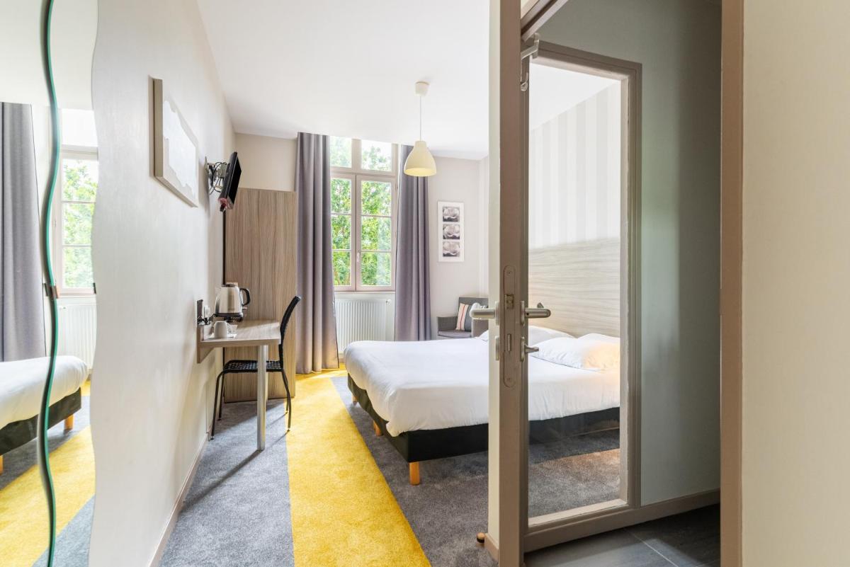 une chambre d'hôtel avec un miroir et un lit dans l'établissement Brit Hotel Spa Le Connetable, à Dinan
