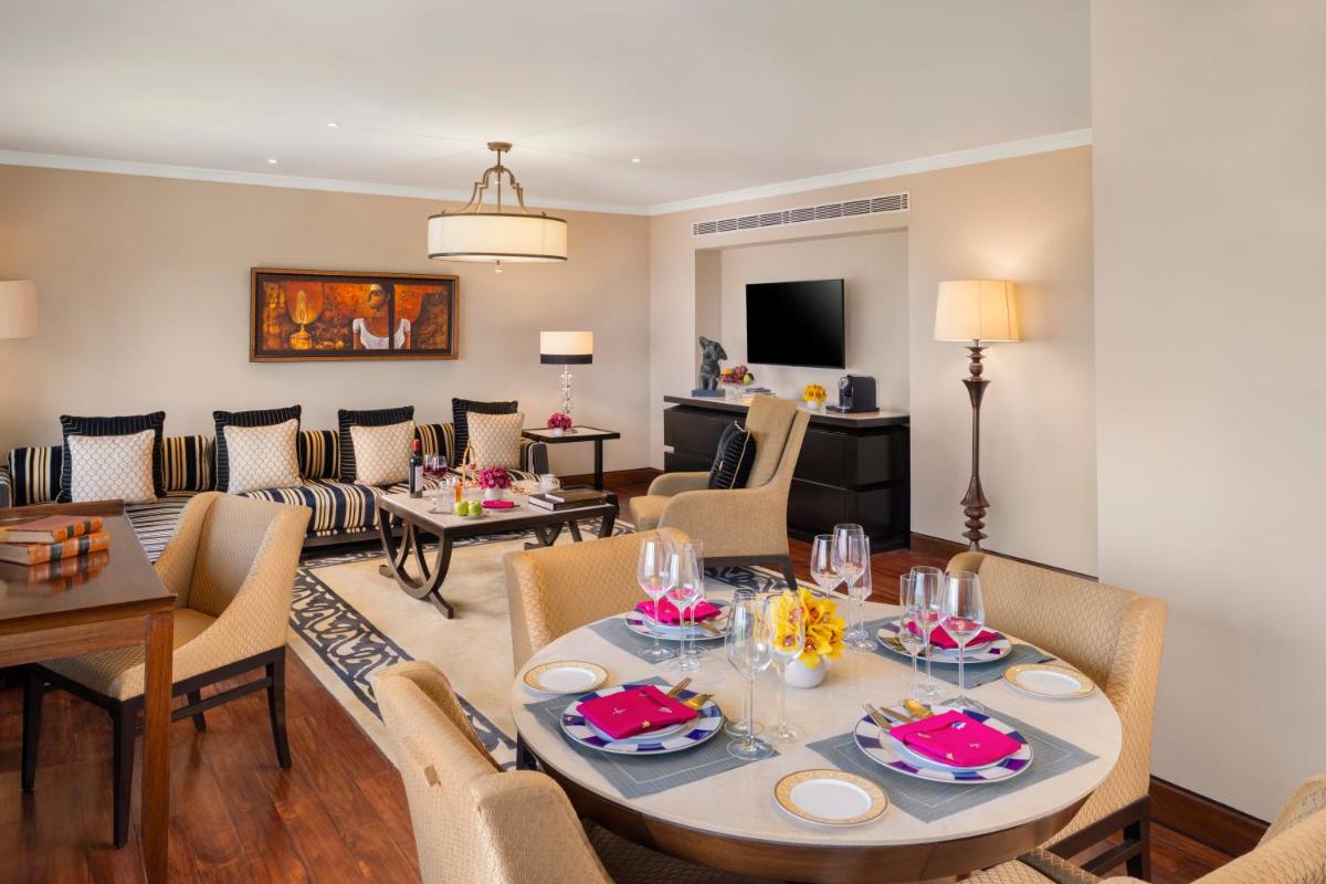 a dining room and living room with a table and chairs at Taj Palace, New Delhi in New Delhi a dining room and living room with a table and chairs at Taj Palace, New Delhi in New Delhi