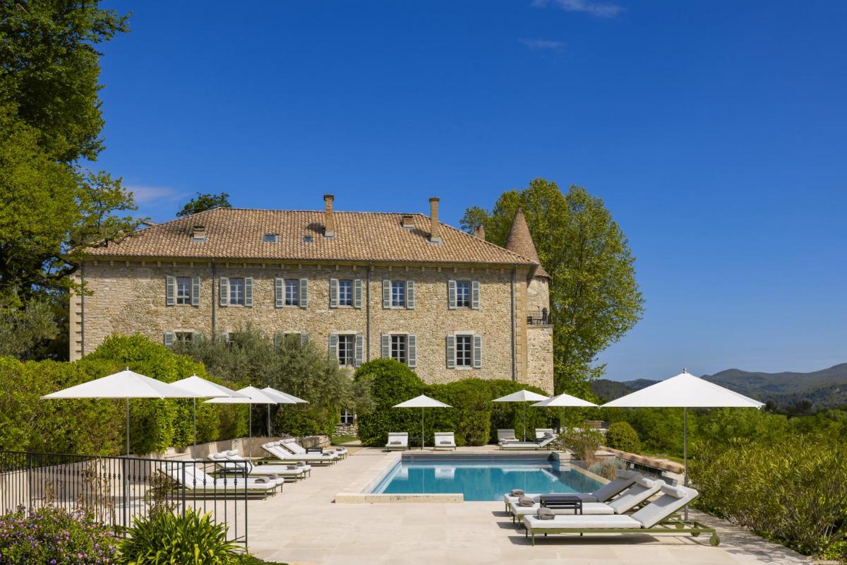 un grand bâtiment avec une piscine équipée de chaises longues et de parasols dans l'établissement Château Les Oliviers de Salettes, à Charols