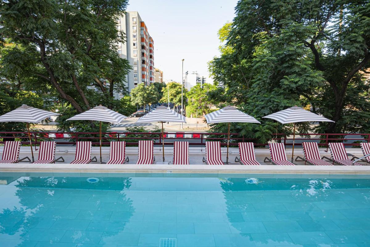 Un grupo de sillas y sombrillas junto a una piscina. en Hesperia Sevilla, en Sevilla