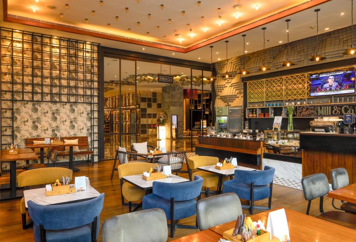 a restaurant with tables and chairs and a bar at Renaissance Ahmedabad Hotel in Ahmedabad