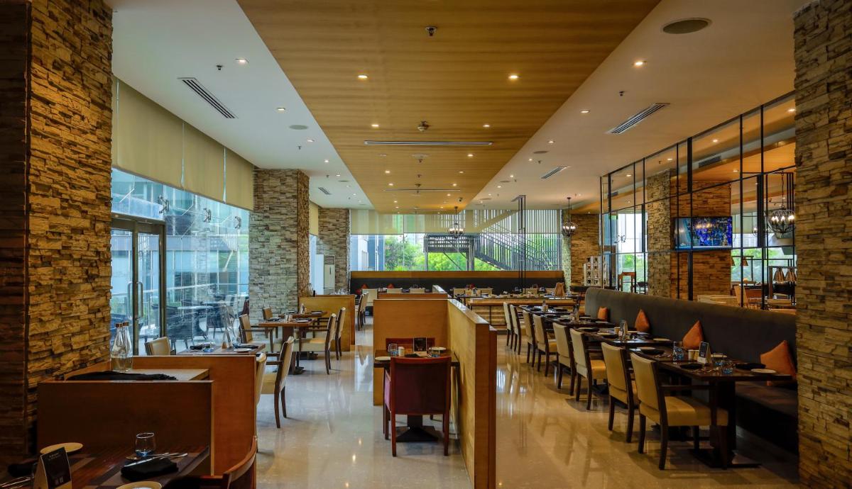 a dining room with tables and chairs and windows at Renaissance Ahmedabad Hotel in Ahmedabad