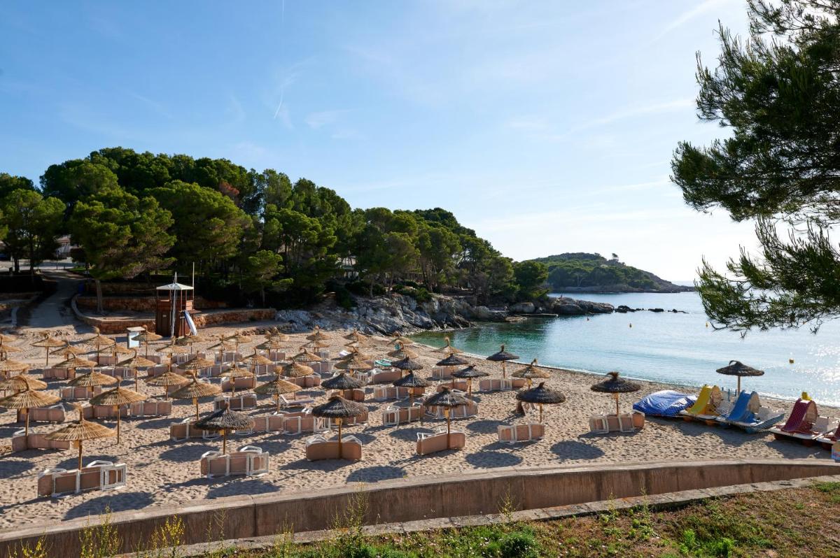 un montón de sombrillas y sillas en una playa en AluaSoul Carolina - Adults Only, en Font de Sa Cala