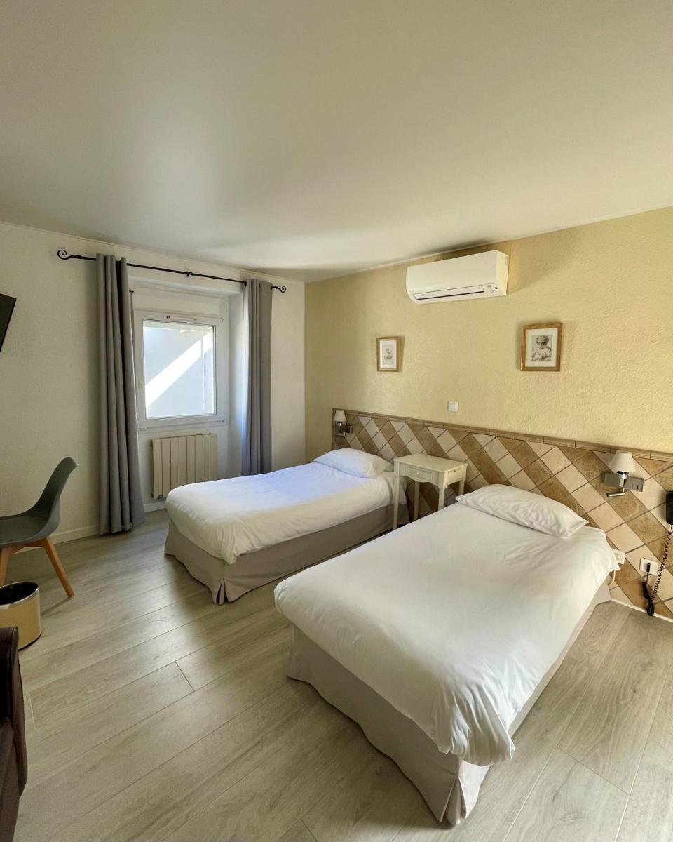 une chambre d'hôtel avec deux lits et une fenêtre dans l'établissement Franceschini, à Ghisonaccia