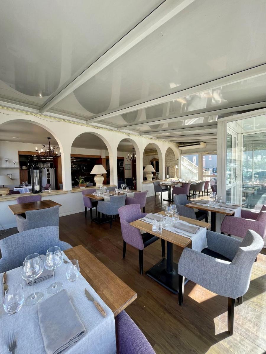 un restaurant avec des chaises, des tables et des fenêtres pourpres dans l'établissement Franceschini, à Ghisonaccia