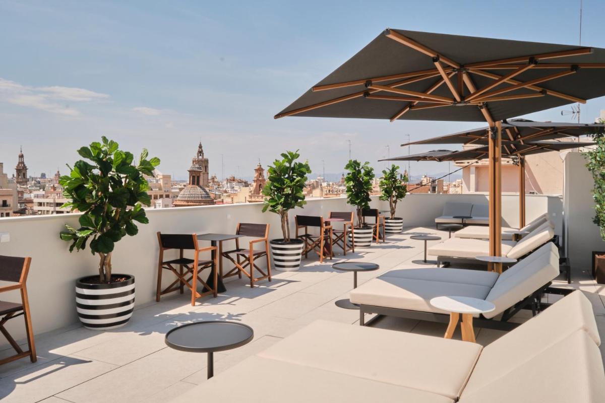 Un patio en la azotea con mesas, sillas y sombrillas. en ESTIMAR Valencia, en Valencia