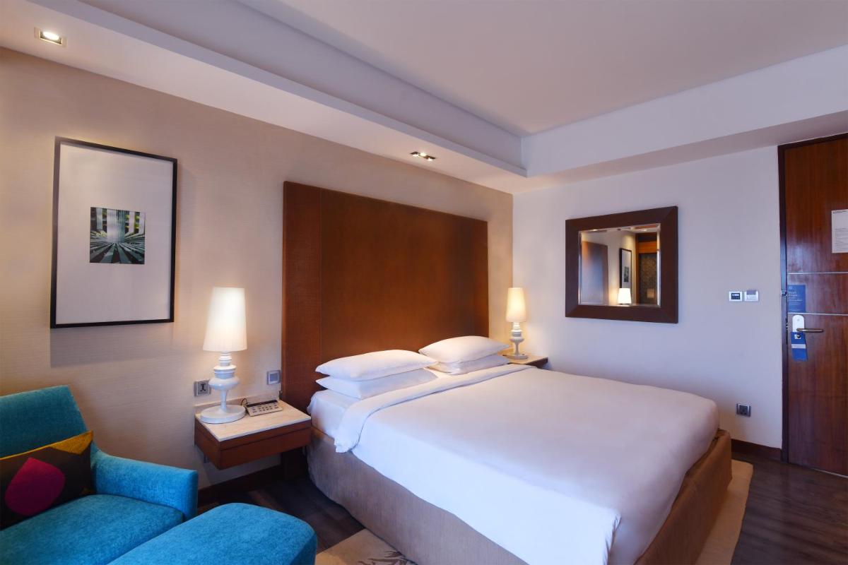 a hotel room with a large bed and a chair at Hyatt Ahmedabad in Ahmedabad