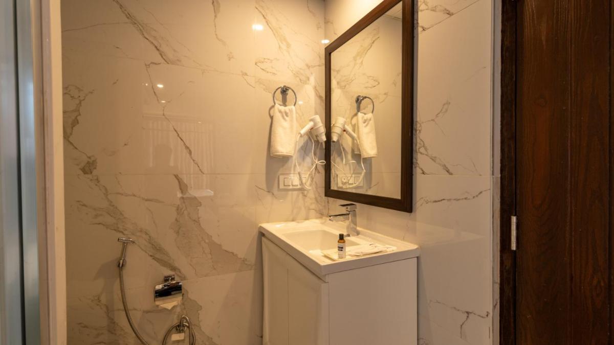 a white bathroom with a sink and a mirror at The Orchid Shimla in Shimla