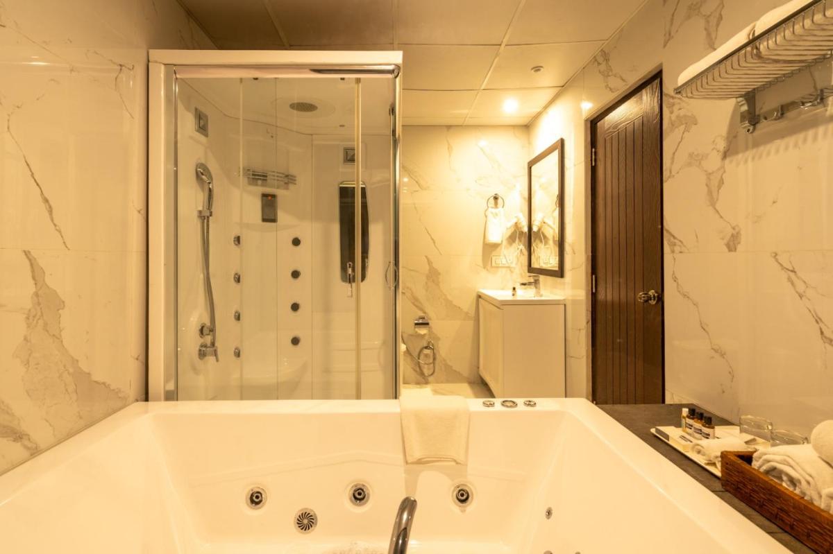a white bathroom with a tub and a shower at The Orchid Shimla in Shimla