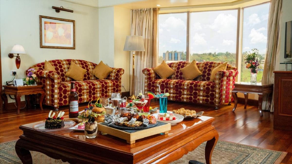 a living room with couches and a table with food on it at Ramada Plaza By Wyndham Palm Grove in Mumbai