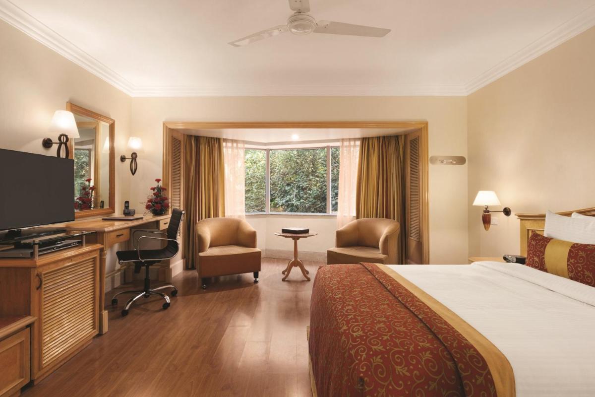 a hotel room with a bed and a desk at Ramada Plaza By Wyndham Palm Grove in Mumbai