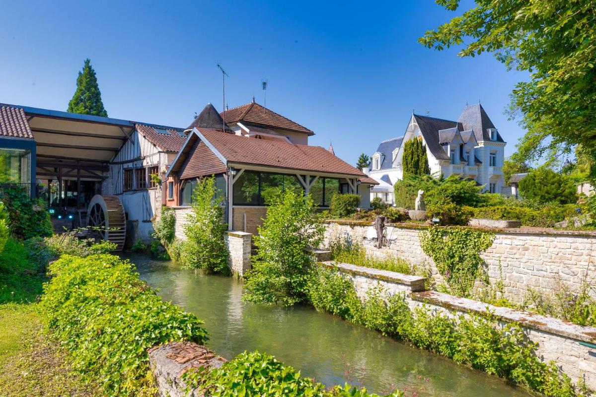 un groupe de maisons au bord d'une rivière dans l'établissement Le Moulin Du Landion Hôtel et Spa, à Dolancourt