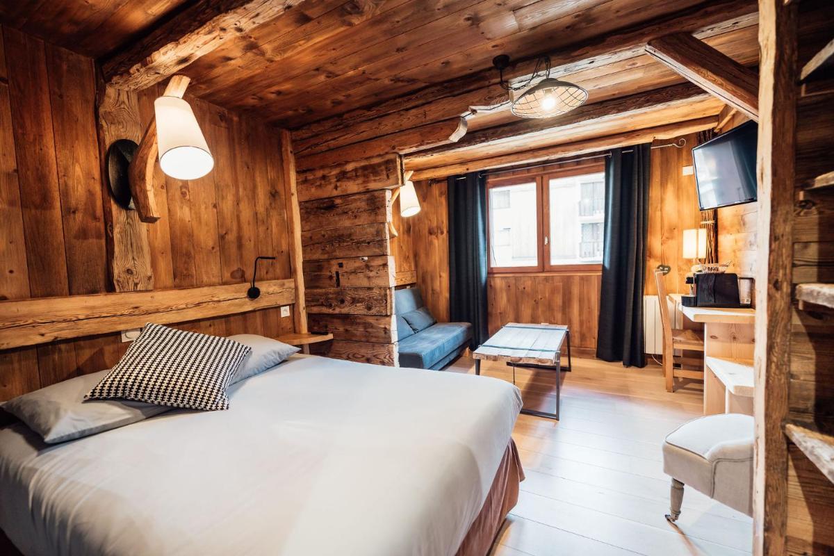 une chambre avec un lit dans une pièce aux murs en bois dans l'établissement Chalet Hôtel du Mont-Charvin & Spa, à Crest-Voland