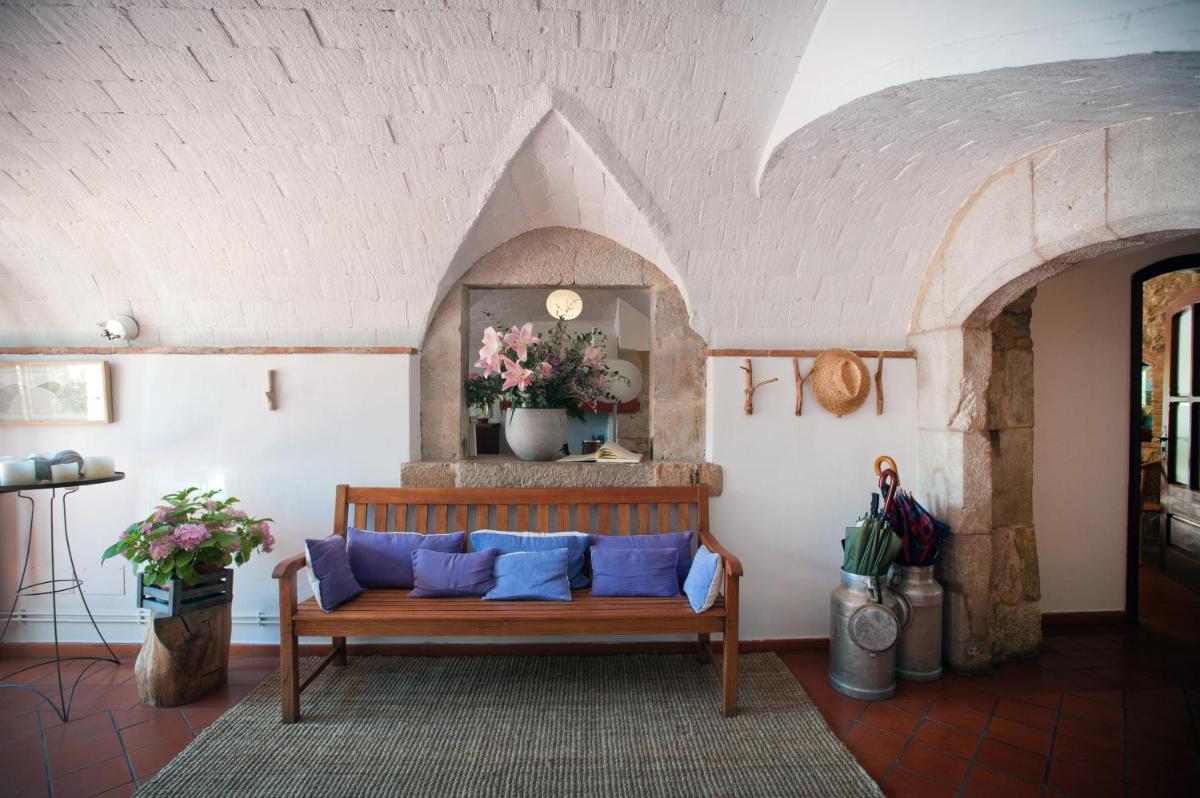 sala de estar con banco de madera y almohadas azules en Mas Falgarona Hotel Boutique & SPA, en Avinyonet de Puigventós 49 fotos más