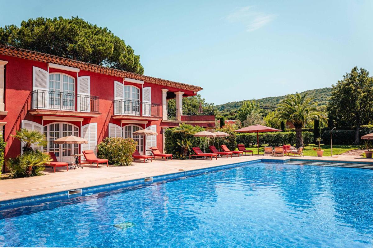 - une piscine en face d'un bâtiment rouge avec des chaises et des parasols dans l'établissement Domaine de l'Astragale, à Saint-Tropez