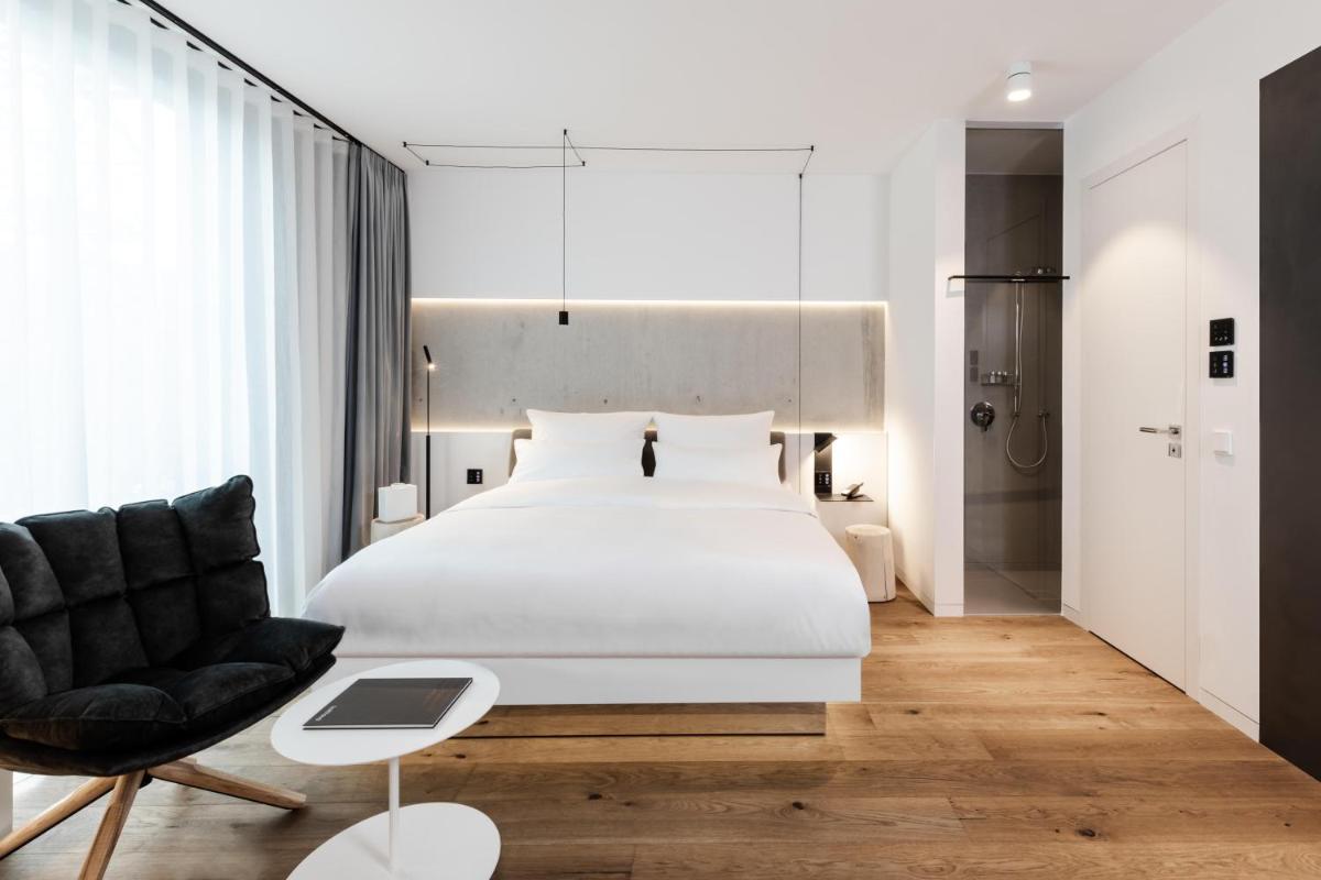 ein Schlafzimmer mit einem großen weißen Bett und einem Stuhl in der Unterkunft KPM Hotel & Residences Berlin, a Member of Design Hotels in Berlin ein Schlafzimmer mit einem großen weißen Bett und einem Stuhl in der Unterkunft KPM Hotel & Residences Berlin, a Member of Design Hotels in Berlin