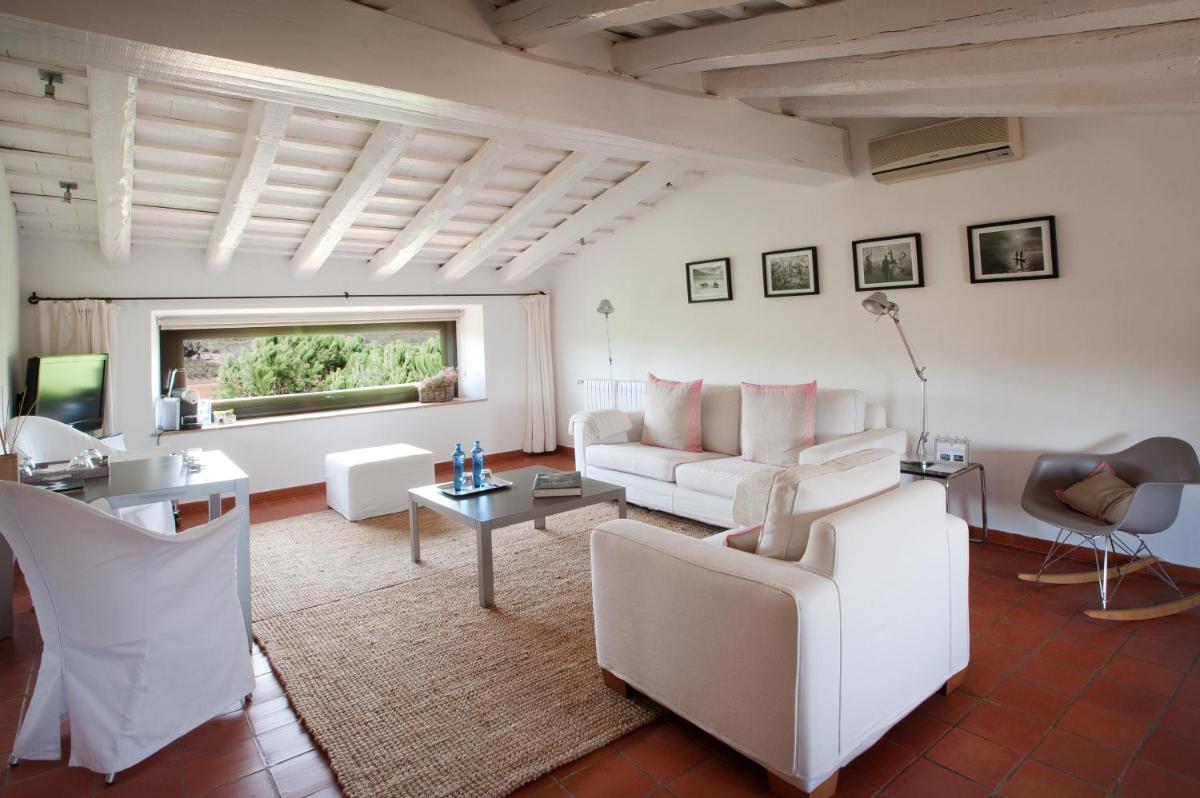 Una sala de estar con muebles blancos y una ventana. en Mas Falgarona Hotel Boutique & SPA, en Avinyonet de Puigventós