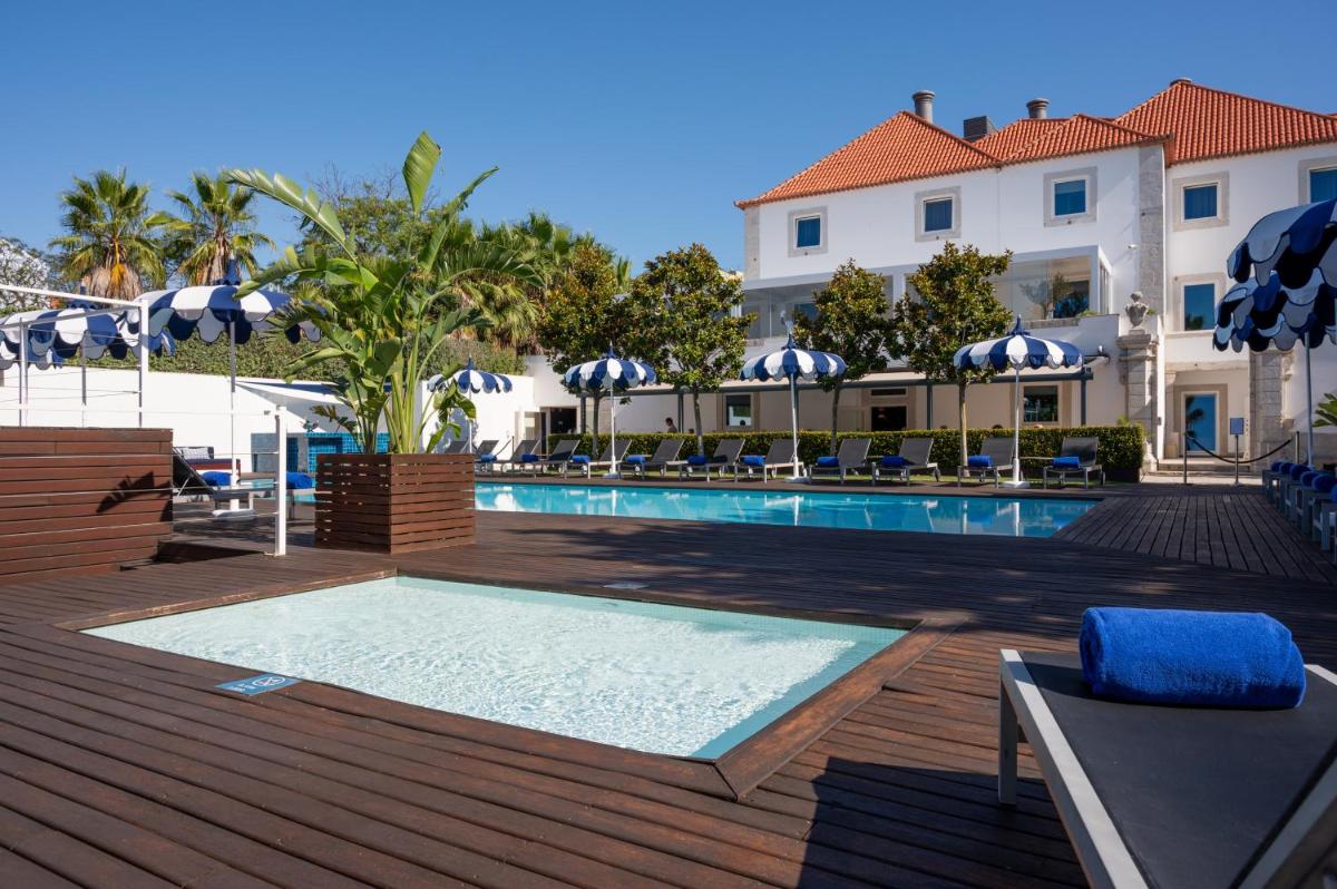 uma piscina com cadeiras e guarda-sóis ao lado de um prédio em Palácio do Governador - Lisbon Hotel & Spa em Lisboa