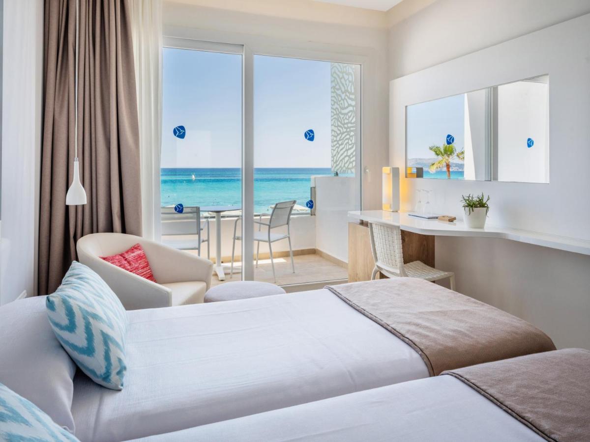 Un dormitorio con una cama y un escritorio con vista al mar. en The Sea Hotel by Grupotel - Adults Only, en Can Picafort