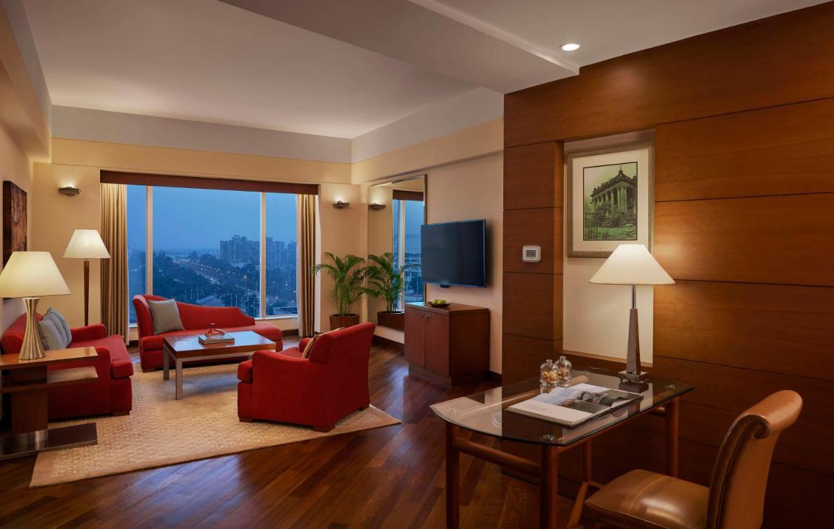 a living room with red furniture and a large window at Hyatt Regency Kolkata in Kolkata a living room with red furniture and a large window at Hyatt Regency Kolkata in Kolkata