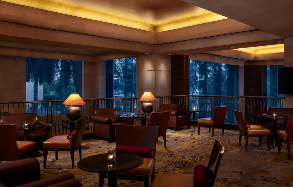a hotel lobby with tables and chairs and windows at Hyatt Regency Kolkata in Kolkata a hotel lobby with tables and chairs and windows at Hyatt Regency Kolkata in Kolkata