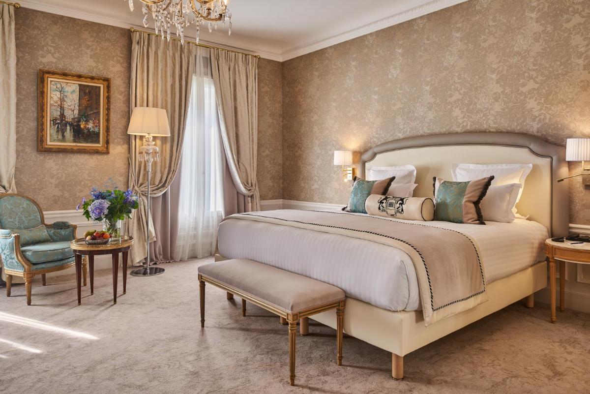 une chambre avec un grand lit et un lustre dans l'établissement Hotel Westminster, à Paris