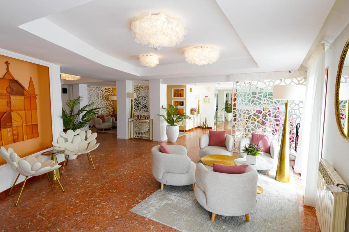 uma grande sala de estar com cadeiras e mesas brancas em Miramar Hotel Spa & Apartments na Nazaré