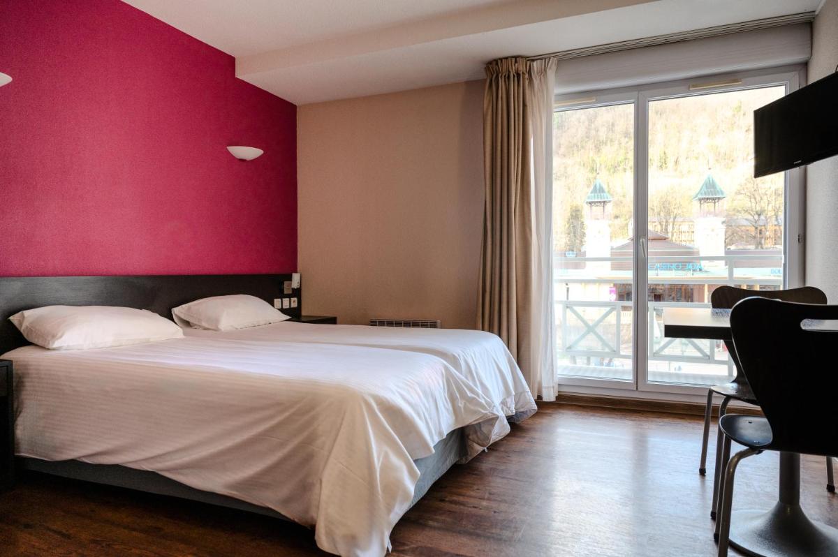 une chambre avec un lit et un mur rouge dans l'établissement Résidence Le Grand Tétras- SPA THERMAL INCLUS, à Ax-les-Thermes 36 autres photos