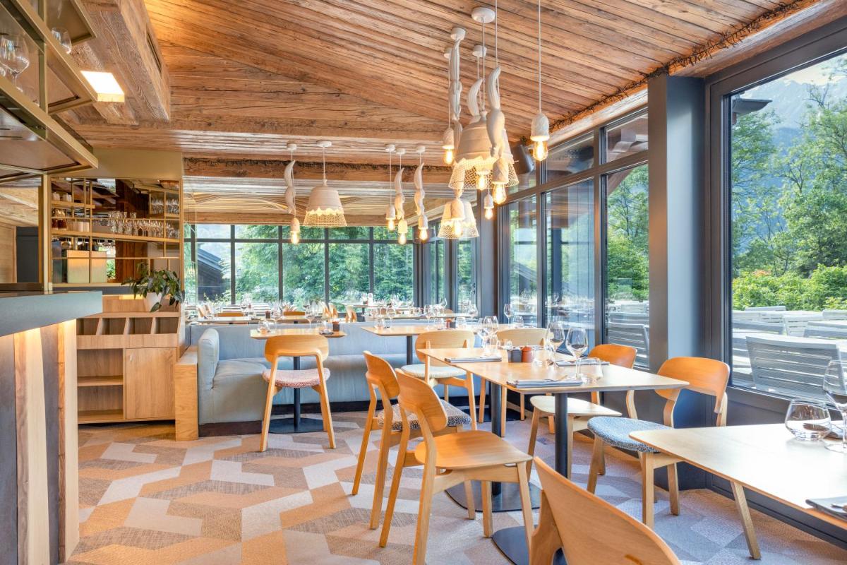 un restaurant avec des tables, des chaises et des fenêtres dans l'établissement Armancette - The Leading Hotels of the World, à Saint-Gervais-les-Bains