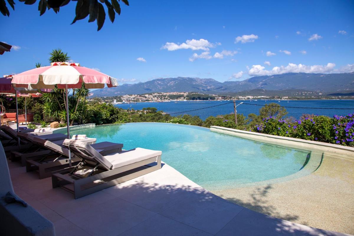 une piscine avec chaises longues et parasol dans l'établissement Hotel Riva Beach, à Porto-Vecchio
