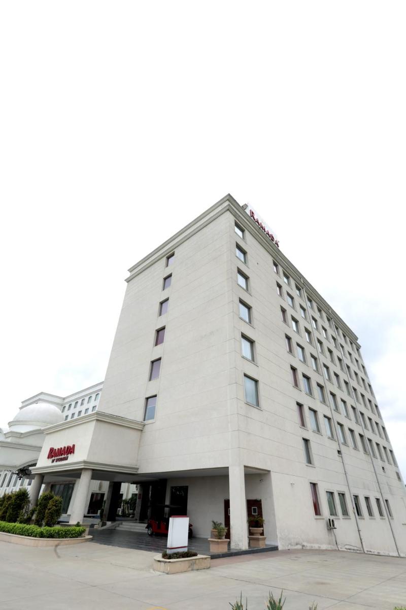 a large white building with a sign in front of it at Ramada by Wyndham Lucknow Hotel and Convention Center in Lucknow