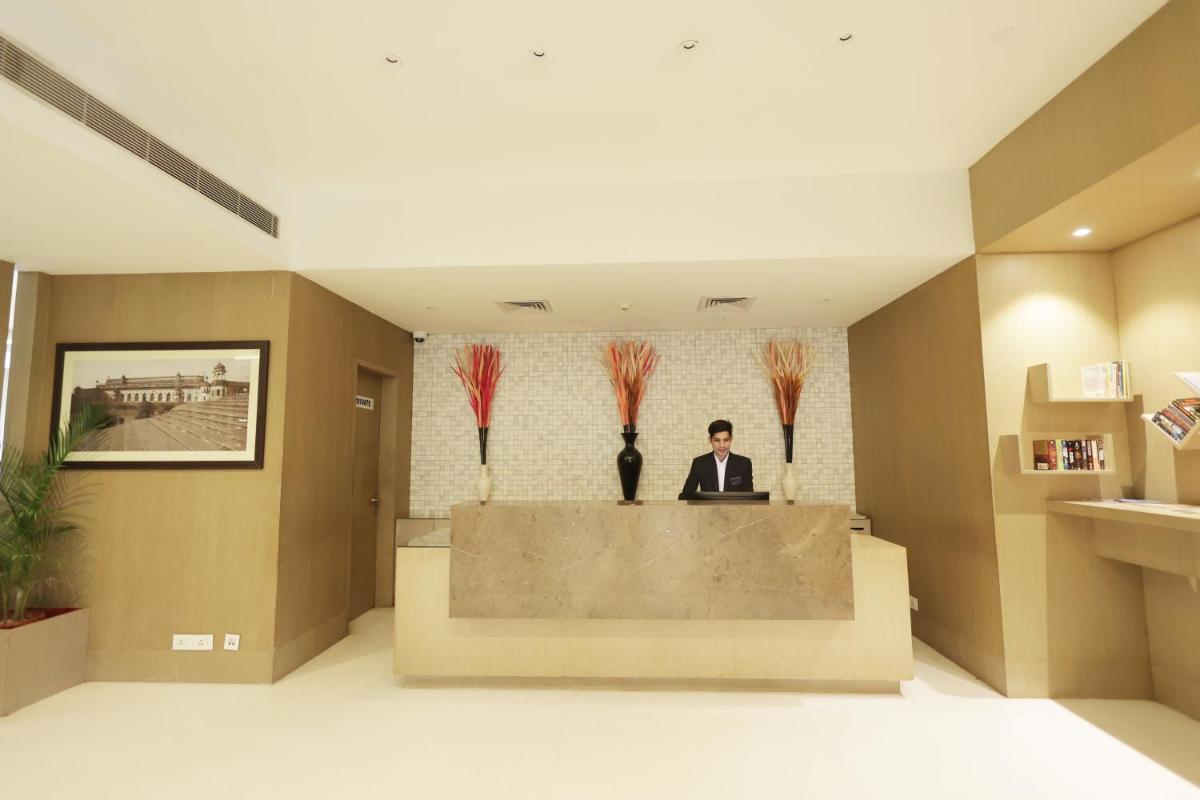 a man sitting at a desk in a lobby at Ramada by Wyndham Lucknow Hotel and Convention Center in Lucknow