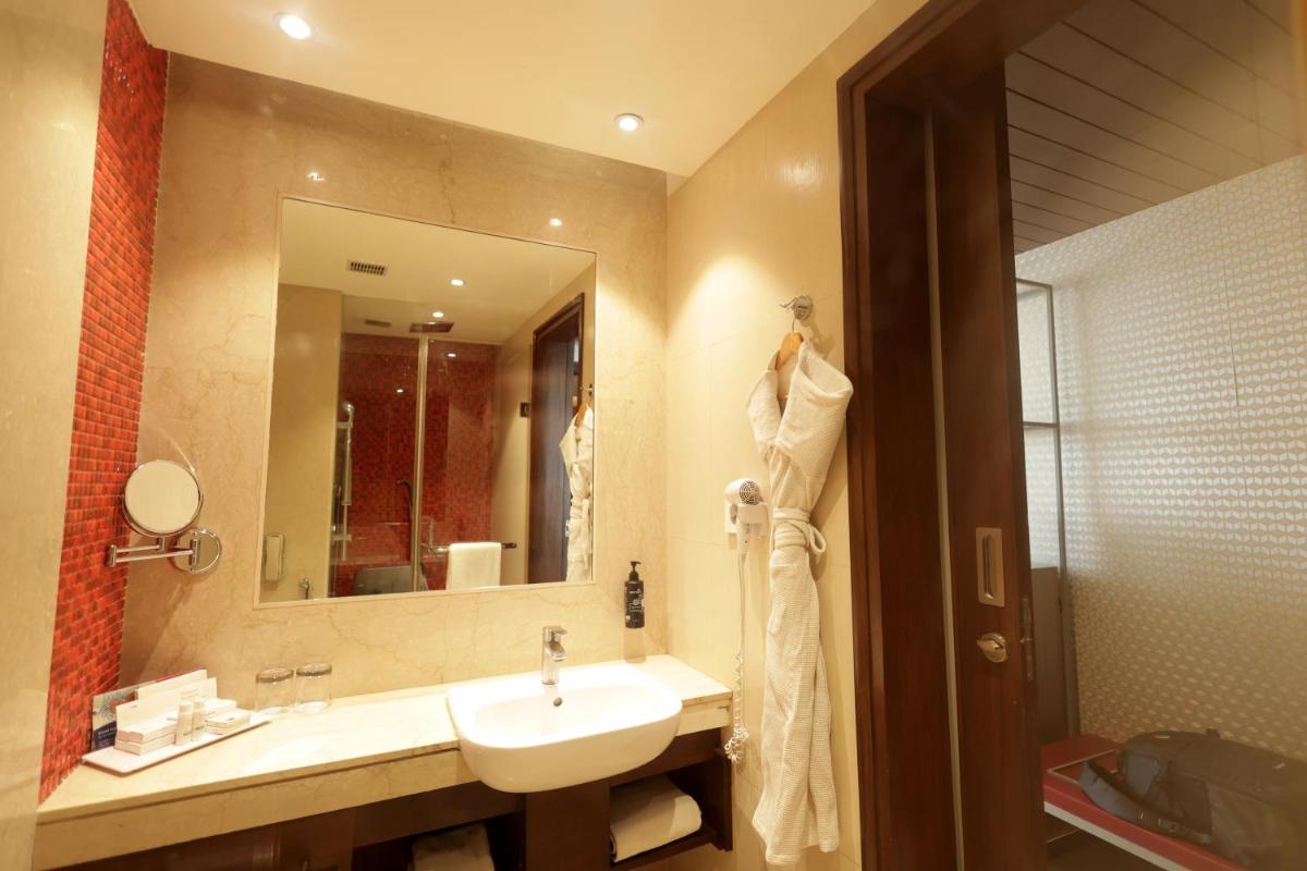 a bathroom with a sink and a mirror at Ramada by Wyndham Lucknow Hotel and Convention Center in Lucknow
