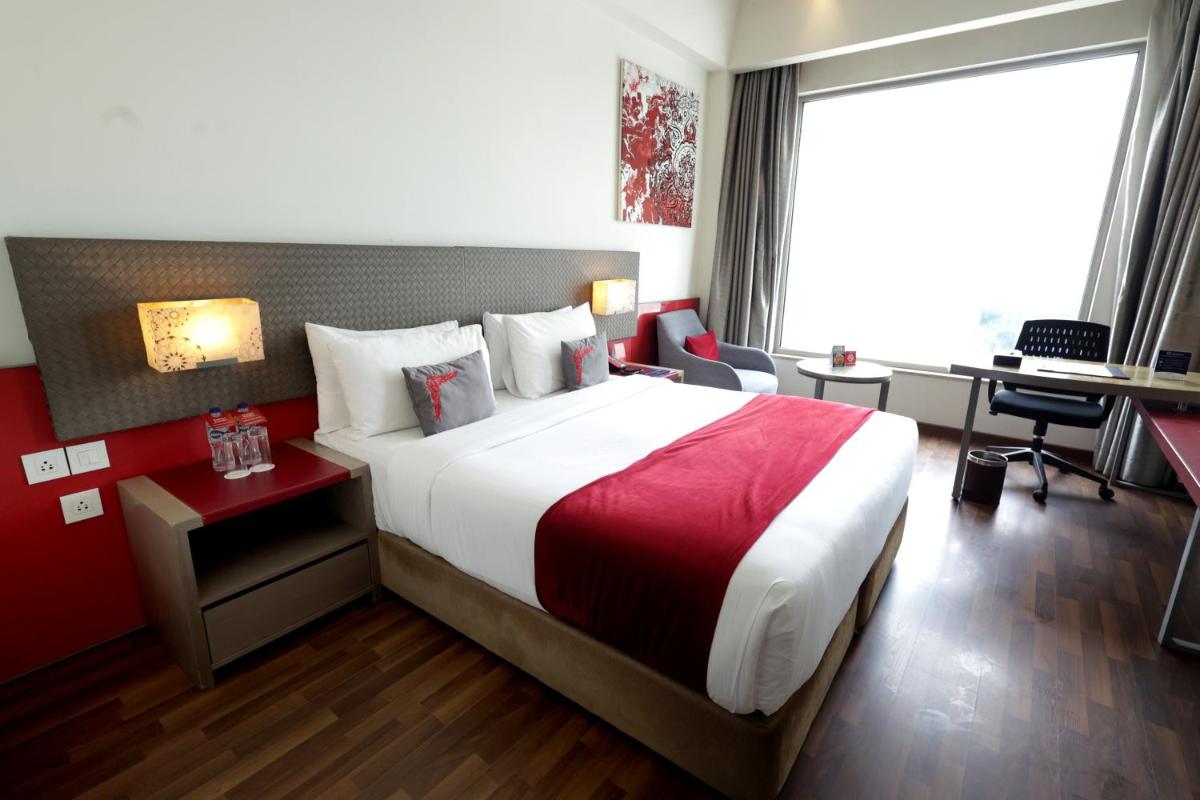 a hotel room with a large bed and a desk at Ramada by Wyndham Lucknow Hotel and Convention Center in Lucknow