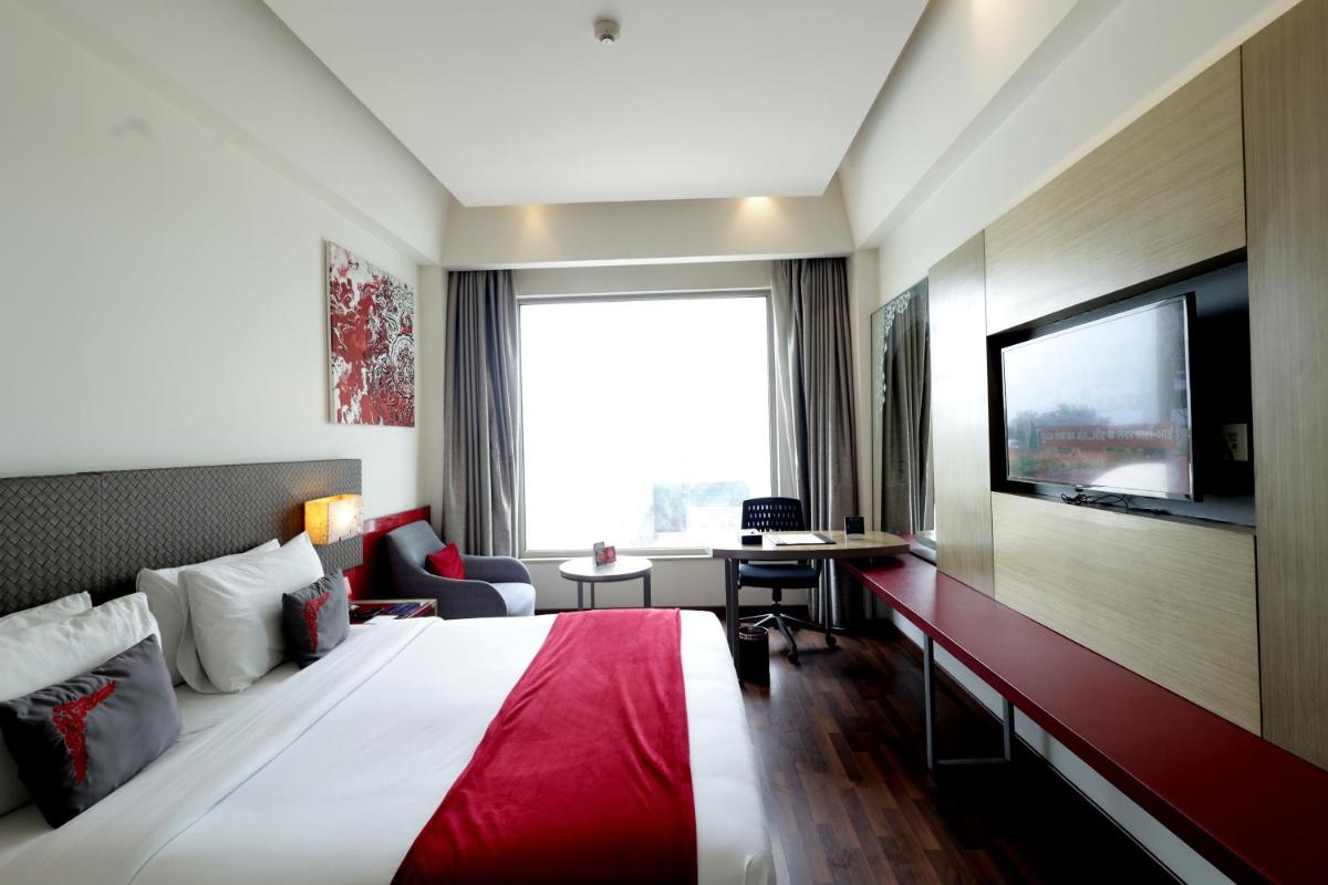 a hotel room with a large bed and a large window at Ramada by Wyndham Lucknow Hotel and Convention Center in Lucknow