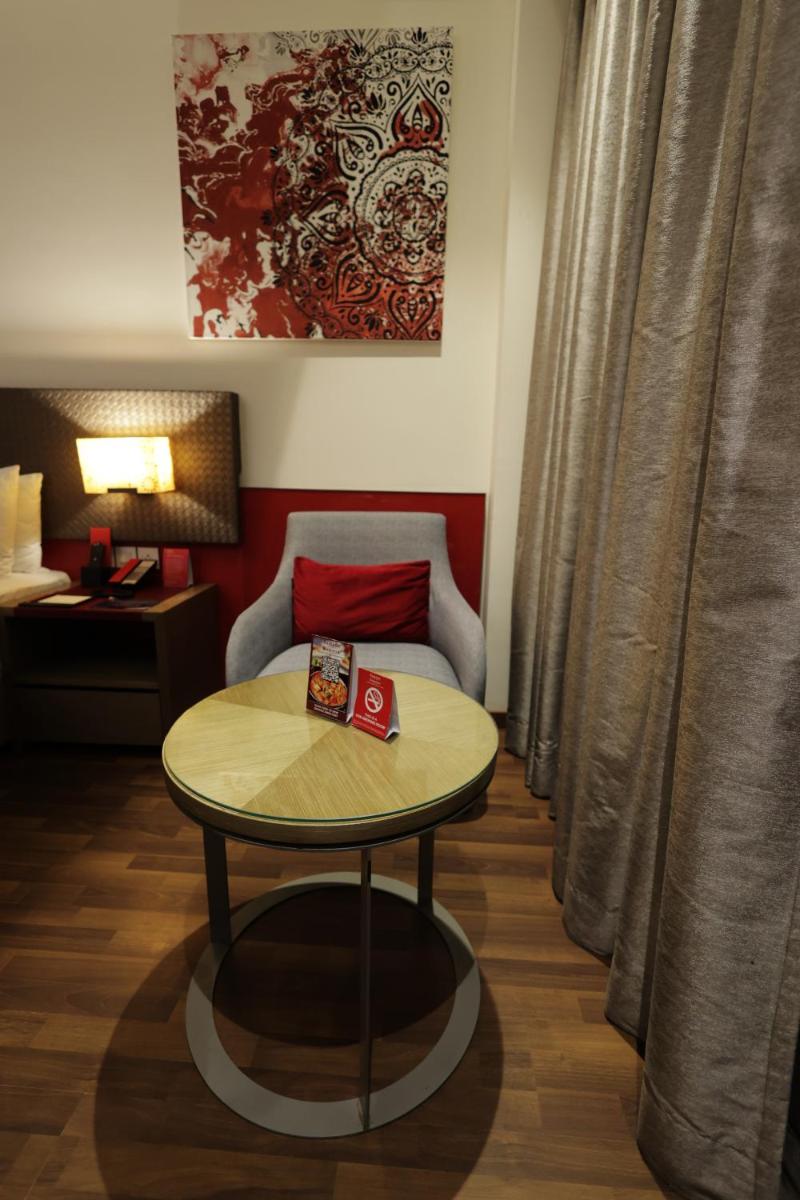 a table in a room with a chair and a bed at Ramada by Wyndham Lucknow Hotel and Convention Center in Lucknow