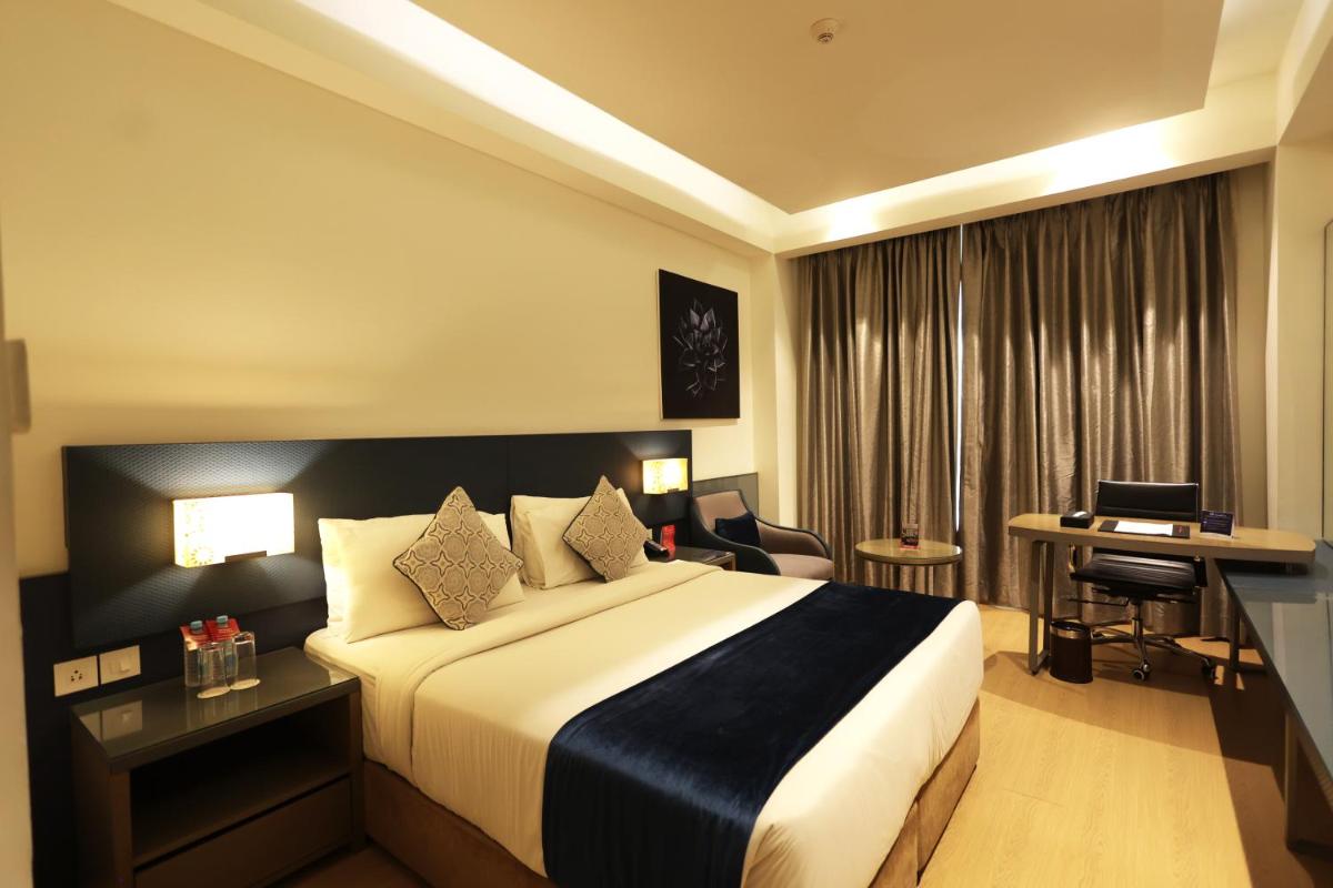 a hotel room with a bed and a desk at Ramada by Wyndham Lucknow Hotel and Convention Center in Lucknow