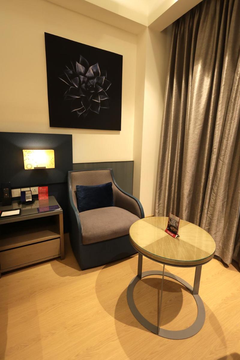 a living room with a chair and a table at Ramada by Wyndham Lucknow Hotel and Convention Center in Lucknow